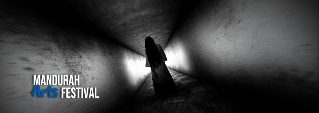 A black and white picture of a long, dark corridor with a ghostly female figure standing eerily